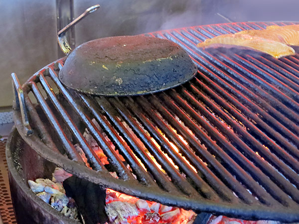 Eine alte Pfanne als Cover auf offenem Grill, z. B. für Fisch